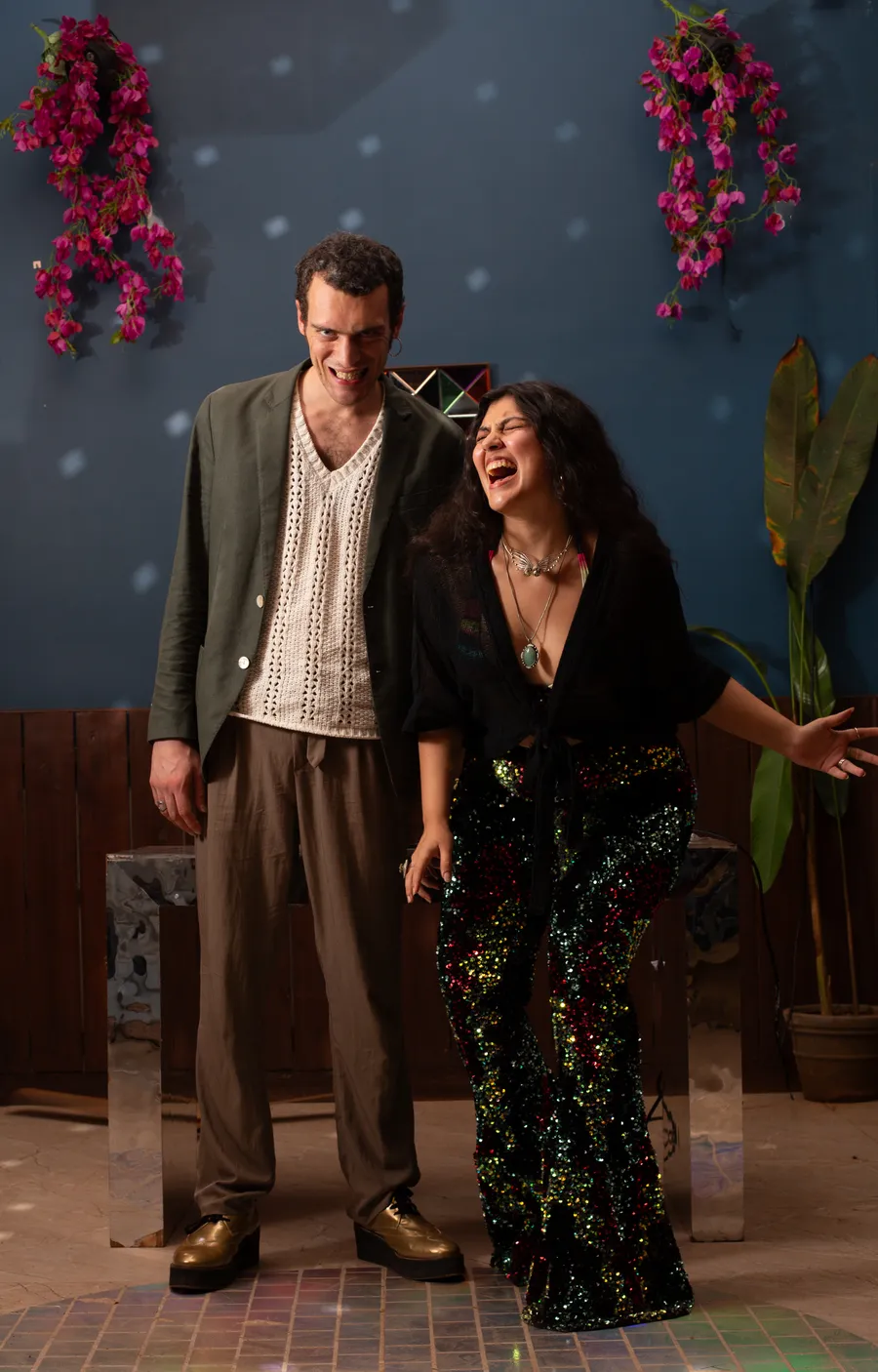 Older woman and young boy laughing together as she holds his arm in a sunlit room with patterned wallpaper.